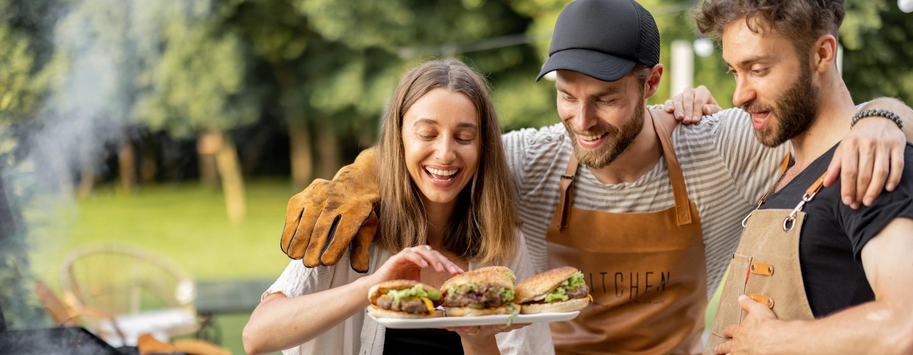 a group of people holding food around a grill