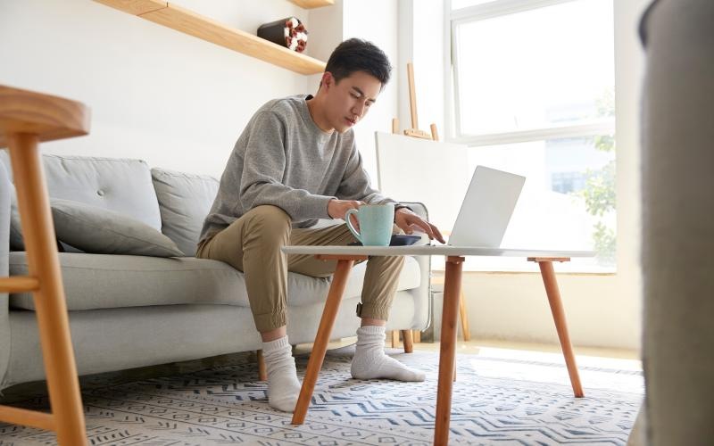 a man sitting on a couch using a laptop